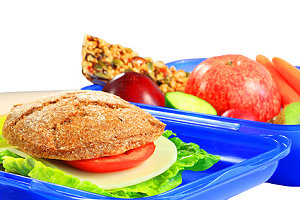 Frühstücksdose oder Brotbüchse mit gesundem Frühstück, Vollkornbrot, Früchte, Gemüse, Müsliriegel. Symbolbild für gesundes Essen.